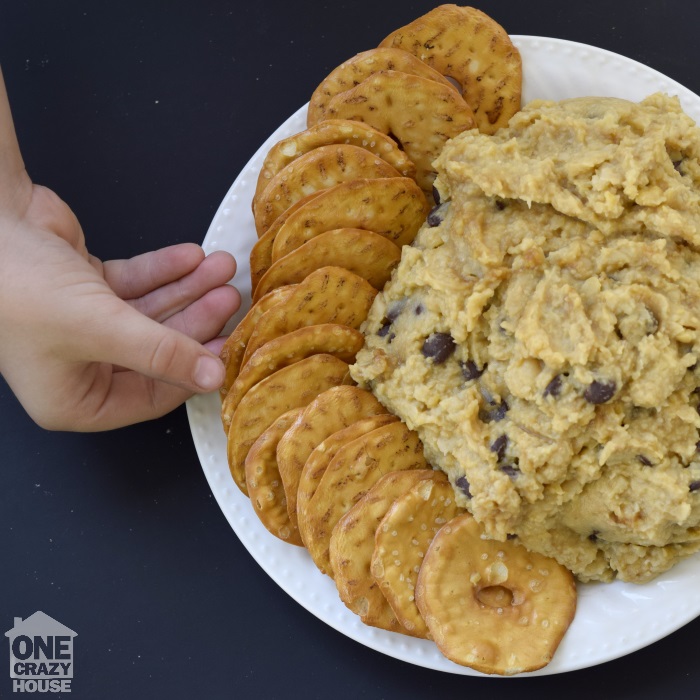 Chocolate Chip Cookie Dough Dip – With a Shocking Ingredient
- Garbanzo Chocolate Chip Cookie Dough served on a white plate with a  side of pretzel chips. 