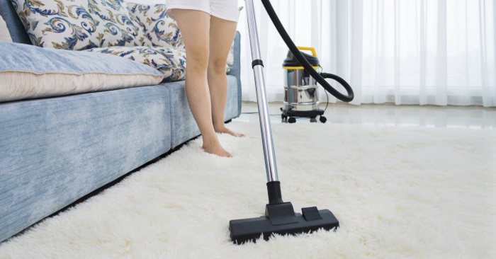 woman vacuuming carpet as part of the spring cleaning list