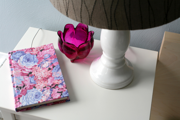 a book atop a white shelf with a charging phone inside