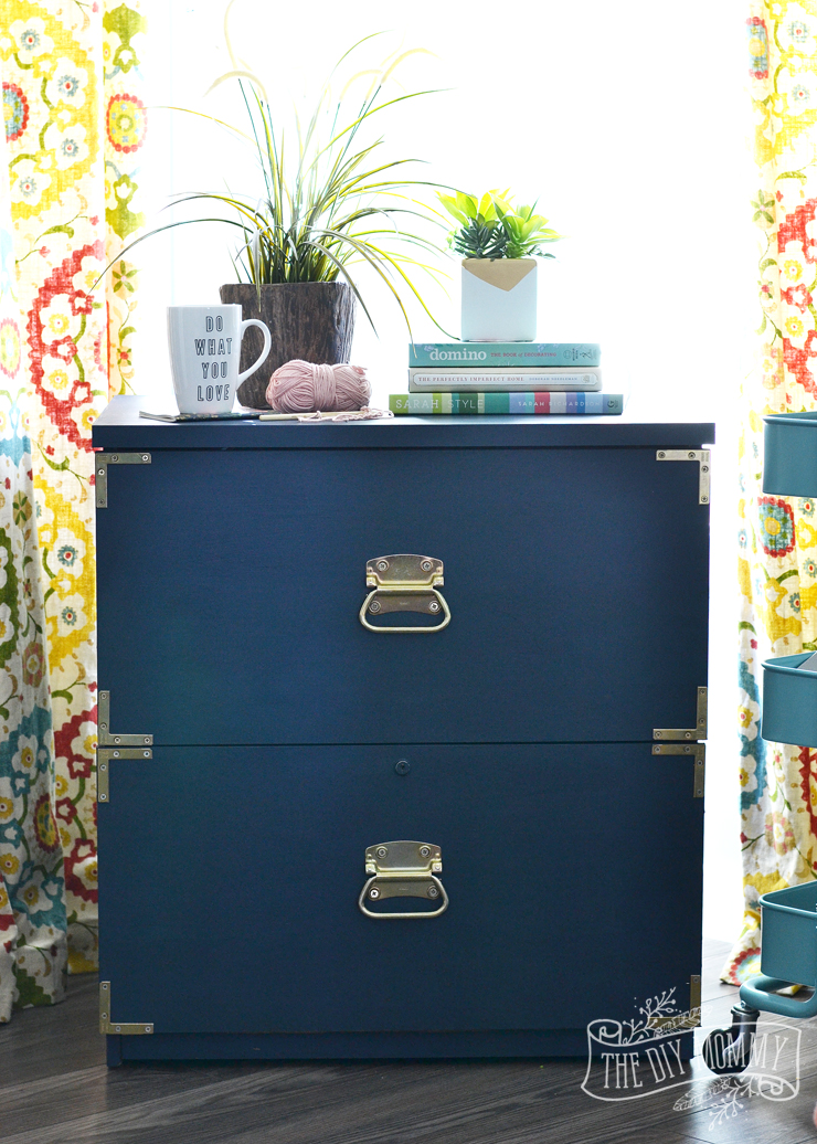 white mug, potted plants, and books on top of a blue dresser filing cabinet