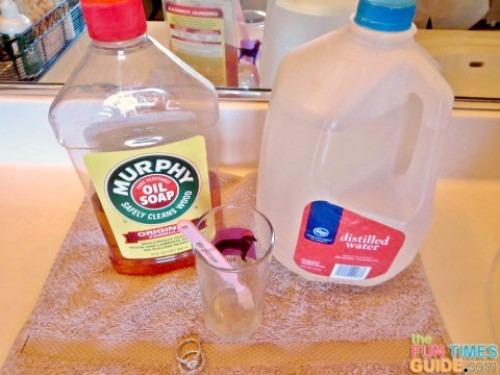 A bottle of Murphy's Oils Soap with a gallon jug of distilled water and a glass with a toothbrush