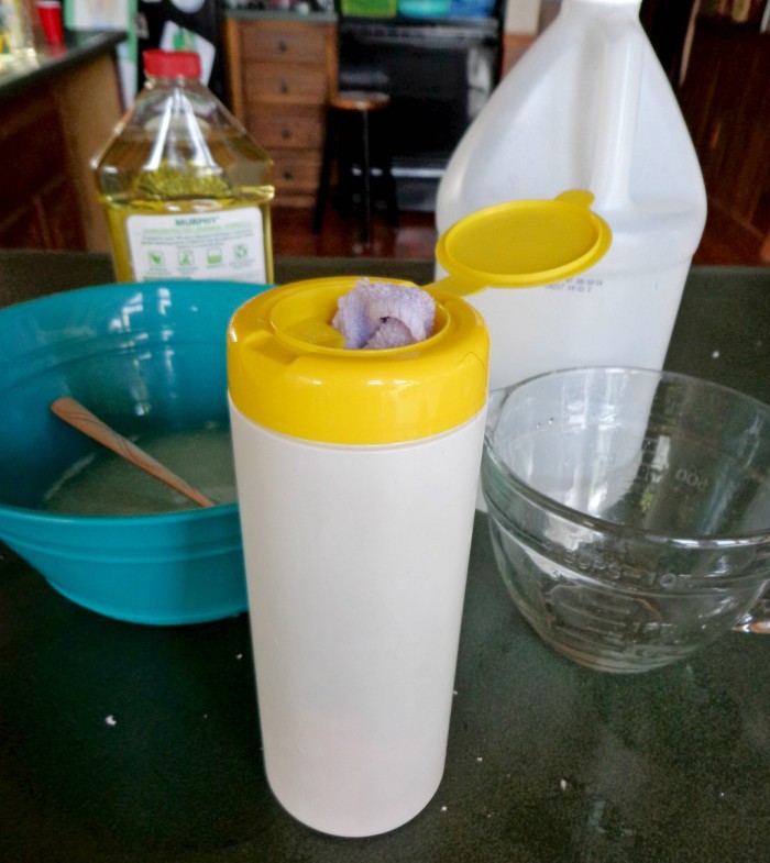 A bottle of Murphy's Oils Soap, white vinegar, a mixing bowl and measuring cup, and a container for handmade wipes.