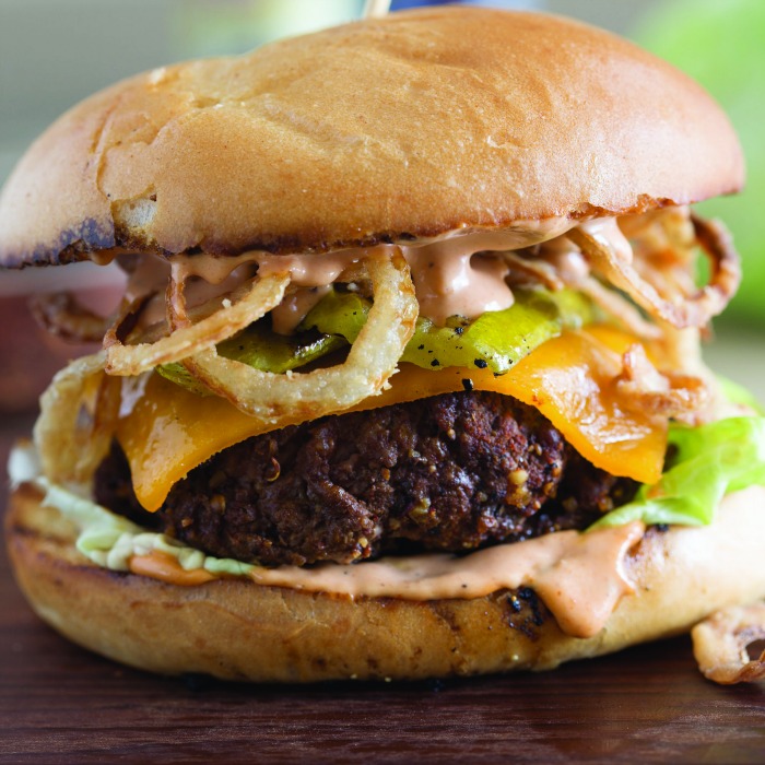 close up of cowboy burger with grilled pickles and crispy onion straws