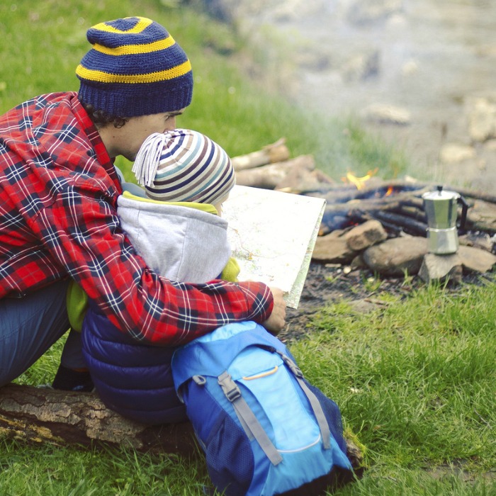 adult sitting in a campsite with a young child