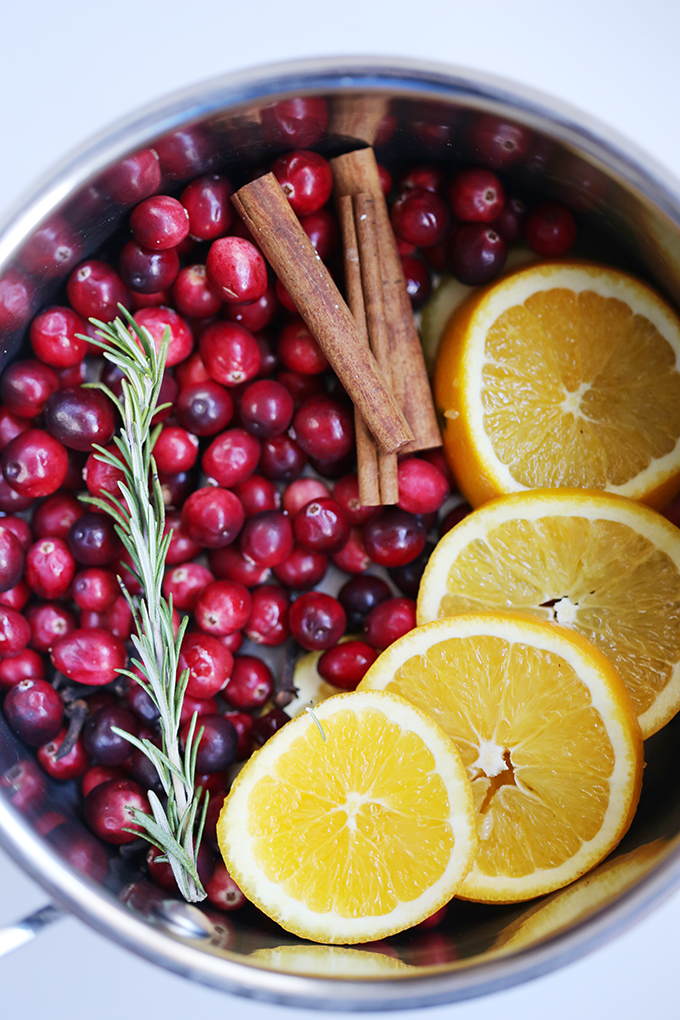 Stovetop pan filled with orange slices, rosemary, cranberries, and cinnamon sticks