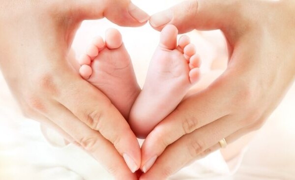 mom holding newborn's feet in a heart shape