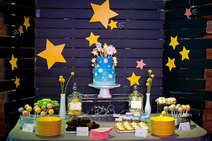 wood slat painted dark blue with yellow stars behind a table full of baby shower desserts