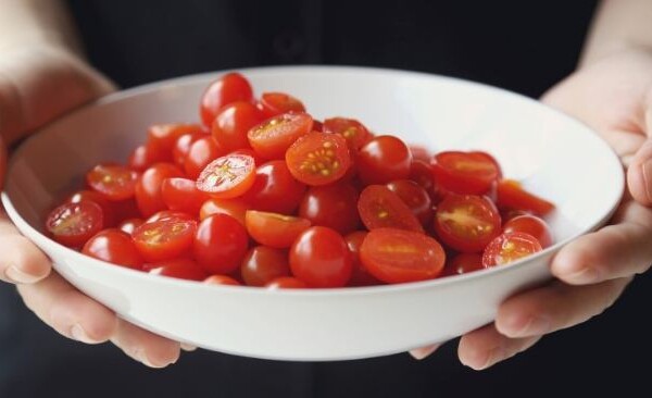 Person holding a bowl of cherry tomatoes