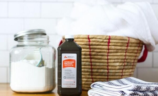 hydrogen peroxide, a canister of baking soda and a basket of towels sitting on a counter