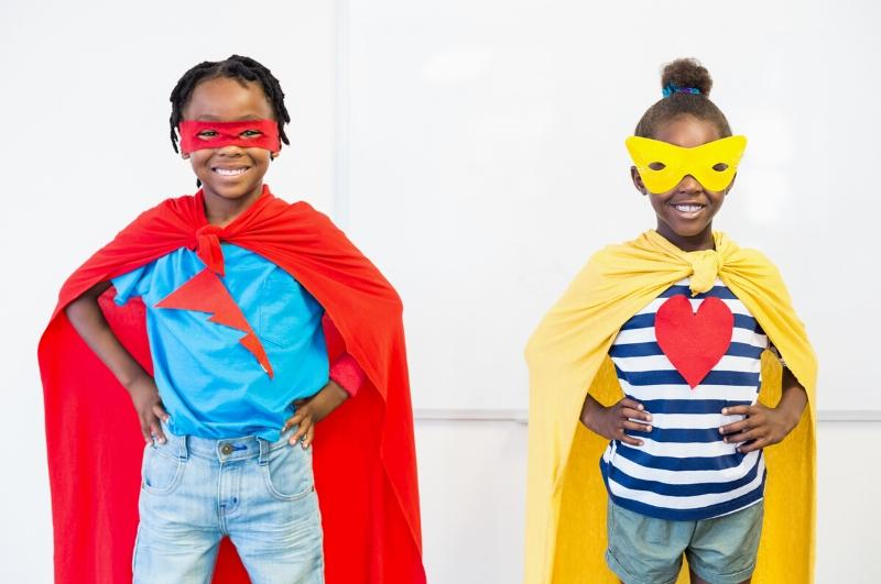 little girl and little boy standing wearing super hero capes and masks