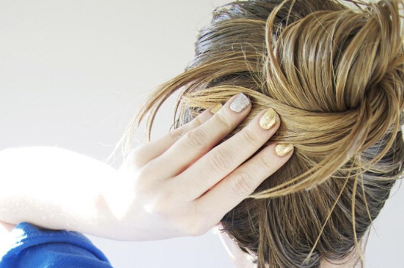 woman tying her long hair into a bun