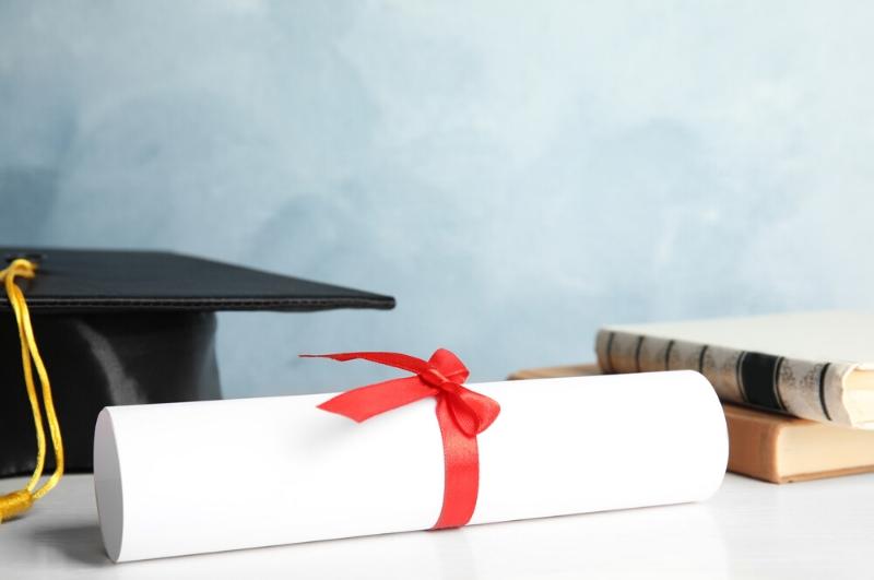 college cap, diploma and books on a table