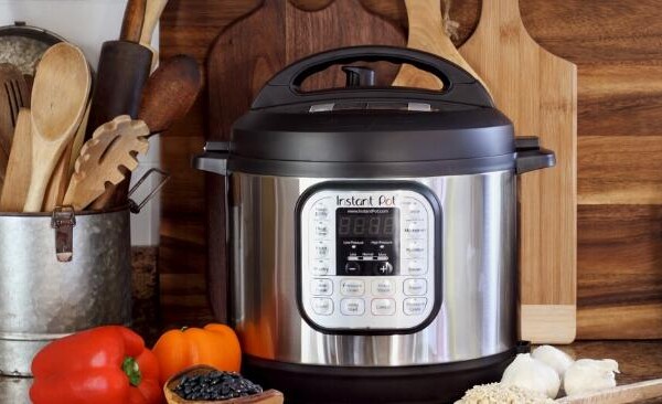 Instant Pot sitting on a counter with peppers, rice, garlic and beans