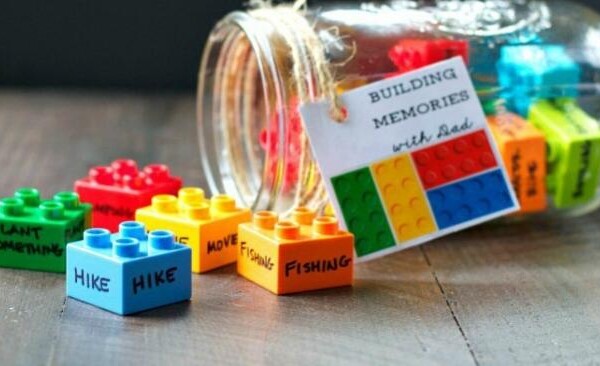 Legos with words written on them spilling out of a mason jar tipped on its side.