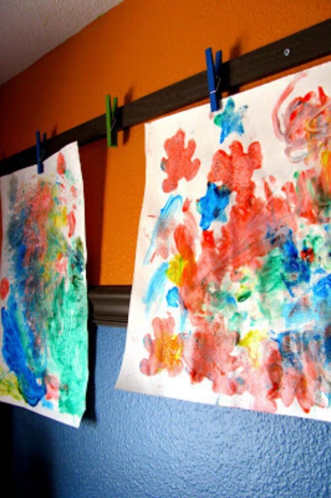 wood strips attached to a wall with clips holding children's artwork