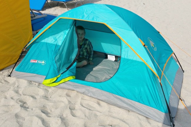 tent set up on a beach with the flap open and a child inside