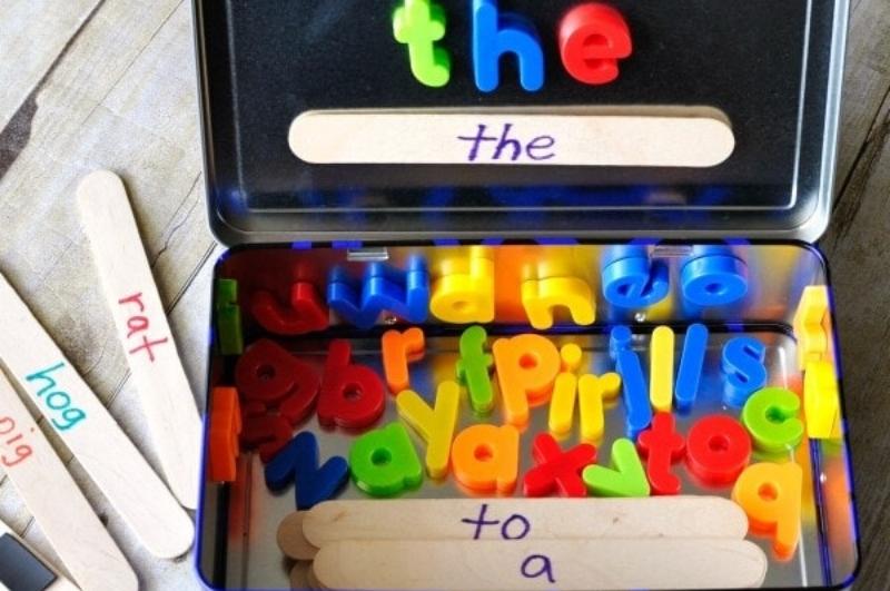 metal lunchbox with magnetic letters and popsicle sticks with words written on them