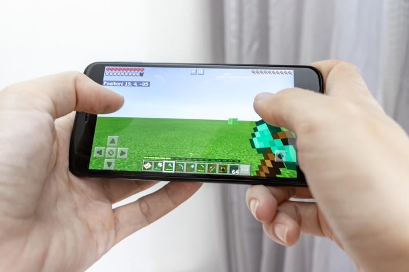 kids hands holding phone and playing Minecraft