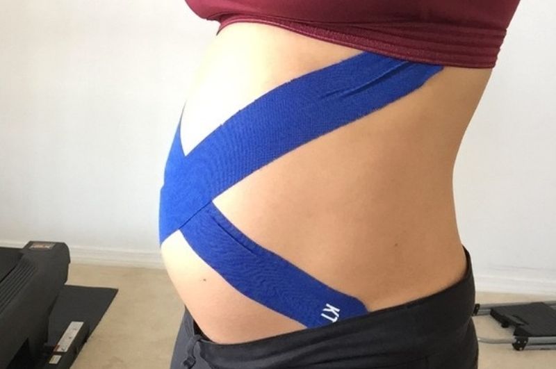 woman using kinesiology tape for pregnancy support