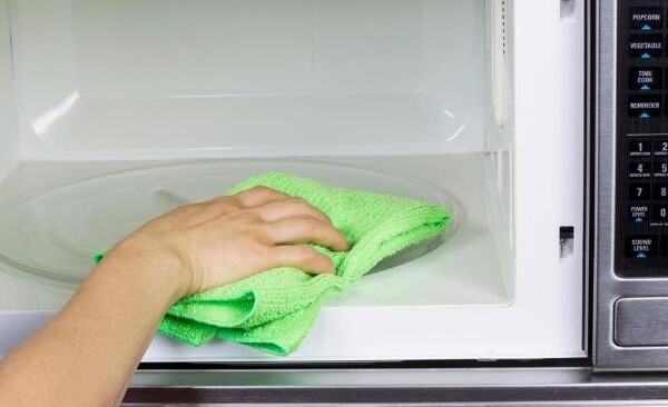 wiping out a clean microwave with a damp rag