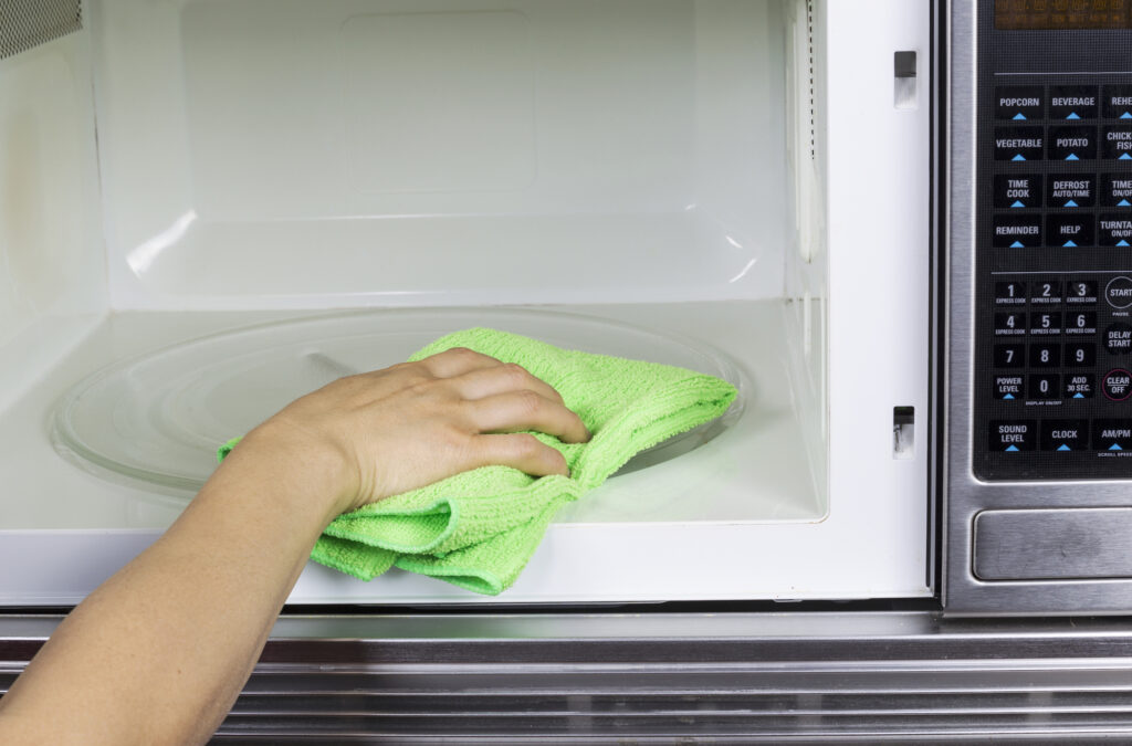 child's hand wiping out a clan microwave with a yellow rag