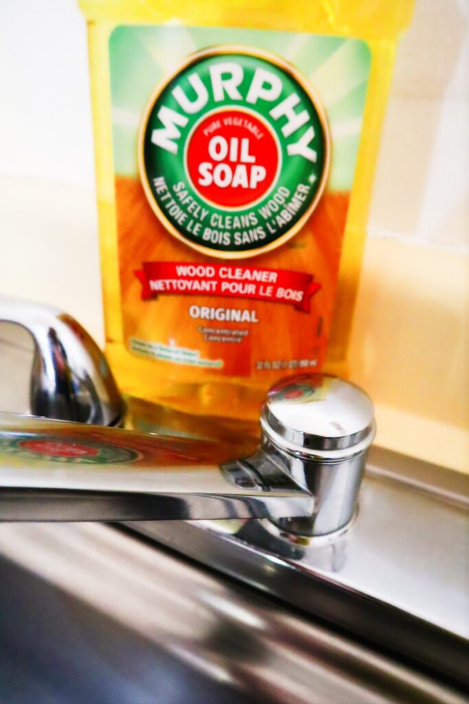 A bottle of Murphy's Oil Soap next to a shiny sink faucet