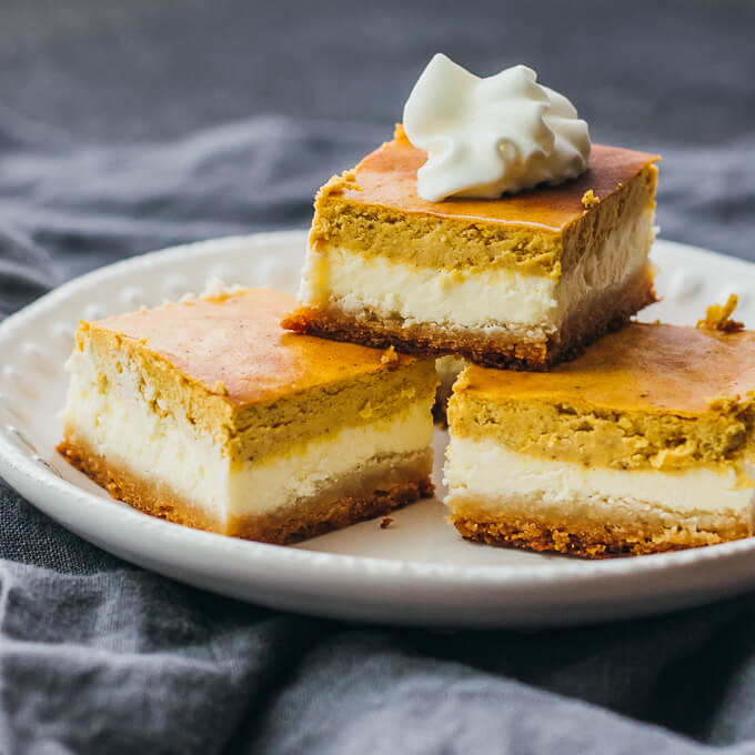 pumpkin cheesecake bars cut in squares and stacked on a plate