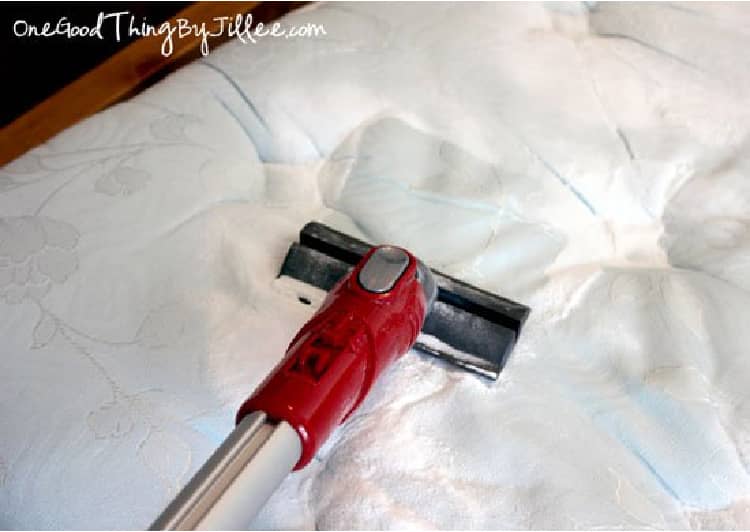 vacuuming a mattress covered with baking soda with essential oils