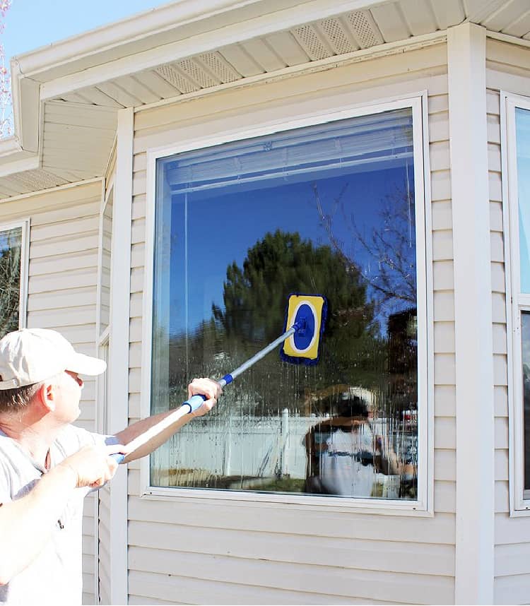 Man cleaning the outside windows with a long-handled brush