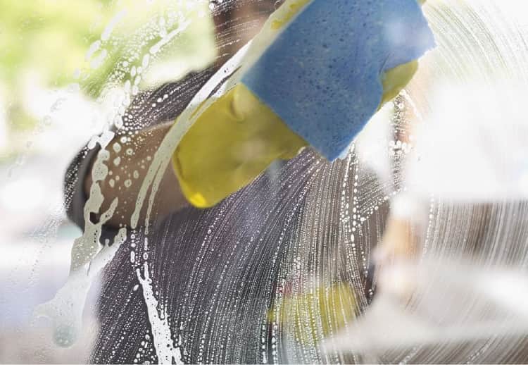 Man washing windows with foamy solution and a sponge