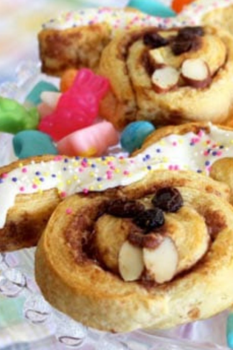 Cinnamon rolls pulled apart and placed into the shape of bunny faces with frosting and fruits to make faces on top