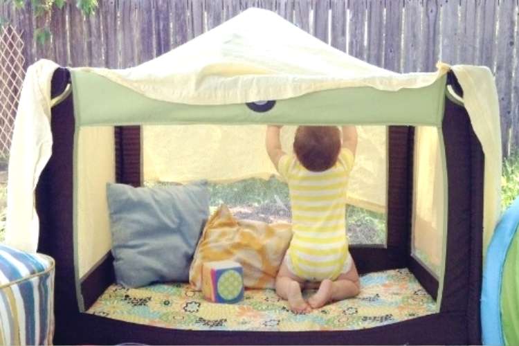 baby in playpen with cover for shade