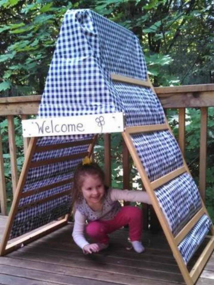 Picture of girl in tent made from on crib sides and crib sheets