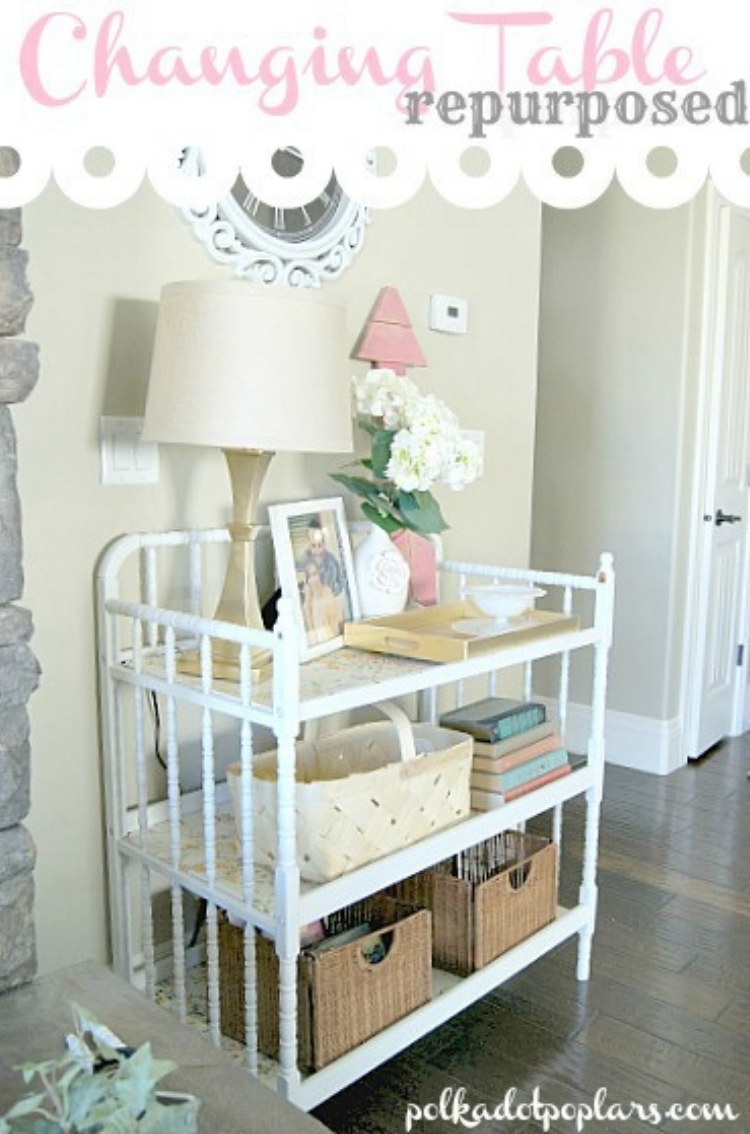 White changing table repurposed into an entry table with baskets, books, lamp and photos