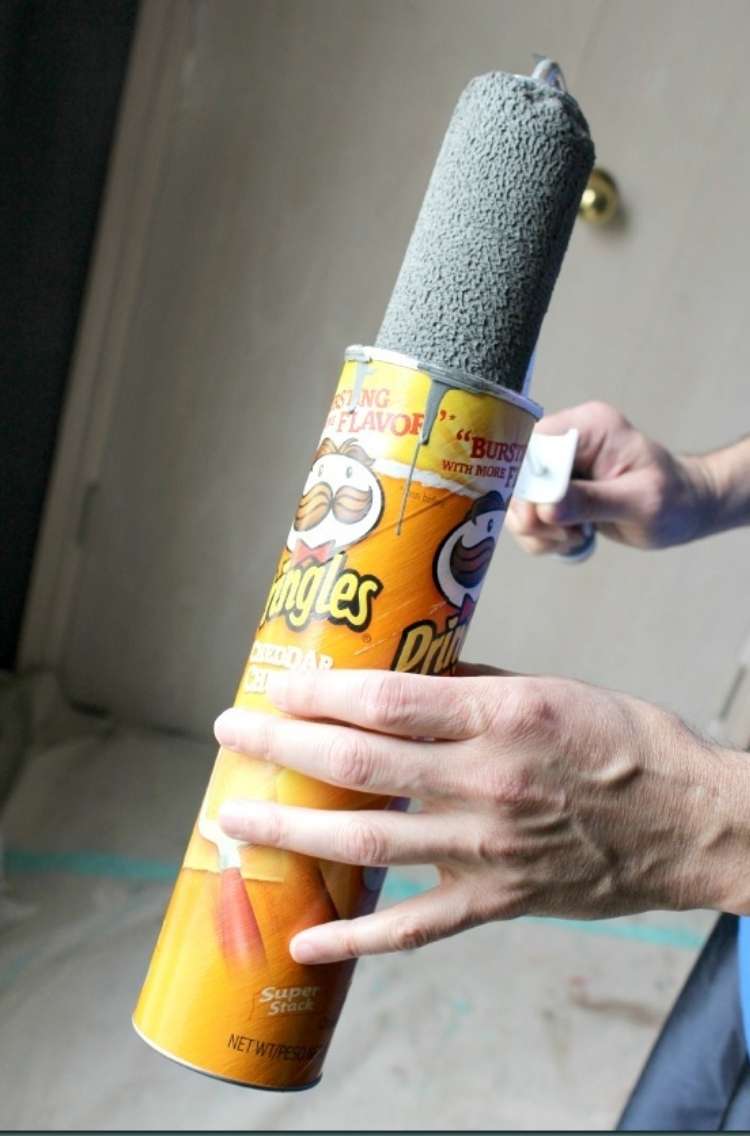 hand holding a can of pringles with wet roller being pulled out of pringles can with paint still wet