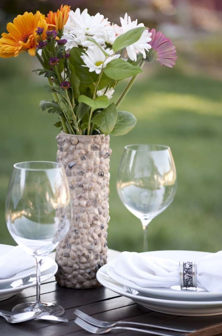  Rock vase made from pringles can on table with plates, silverware, wineglasses and cloth napkins inside napkin holder on plates