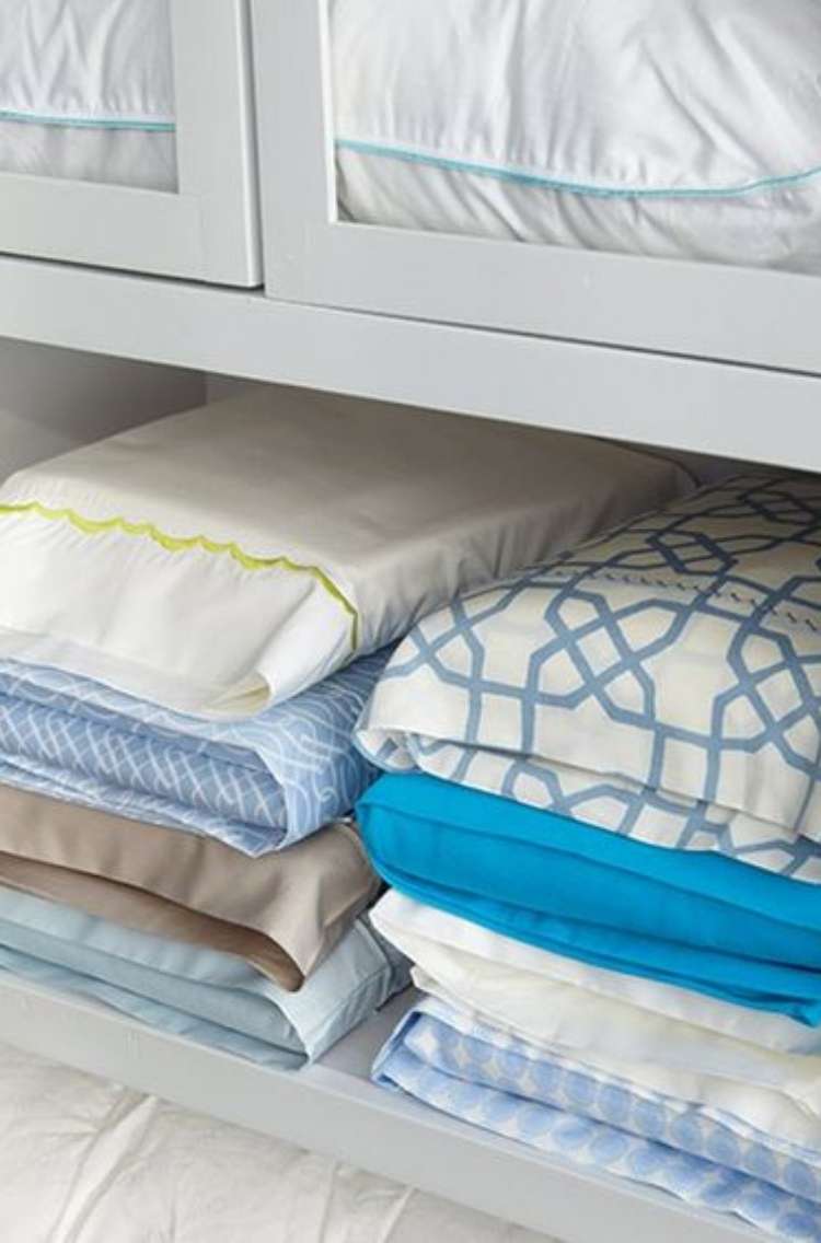 Linen closet with 8 sheet sets stored inside corresponding pillowcase stacked neatly on a shelf 