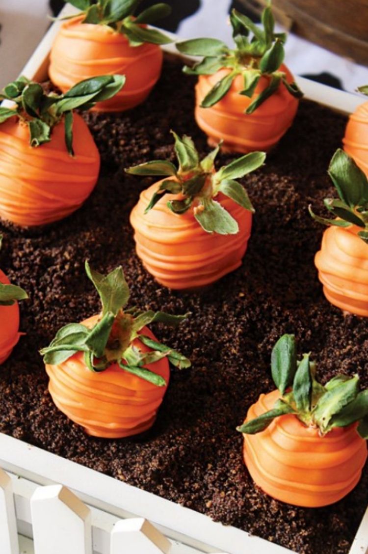 Orange Chocolate covered strawberries made to look like carrots in a crumbled cookie mix bed