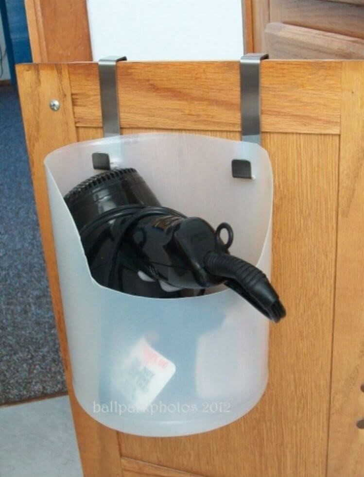 Under bathroom sink storage - repurposed jug turned into blow dryer container hanging over bathroom vanity door