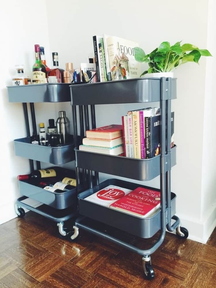 two dark grey rolling carts, one with differnt bottles of alcohol and wine and the other with cookbooks