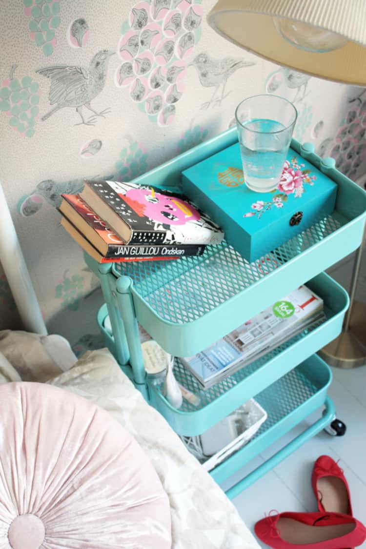 an ikea cart used as a nighttable with books and water