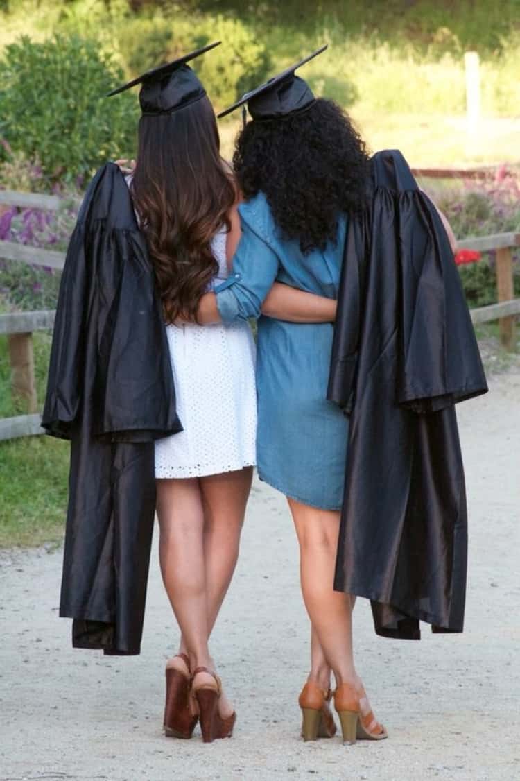 senior picture ideas for girls - 2 girls casually adorned in graduation caps and gowns facing away from the camera