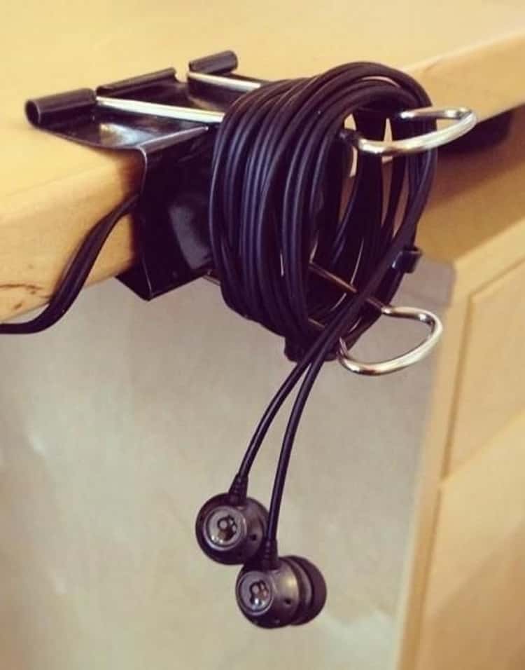 binder-clip-earbuds holder clipped to the edge of a desk 