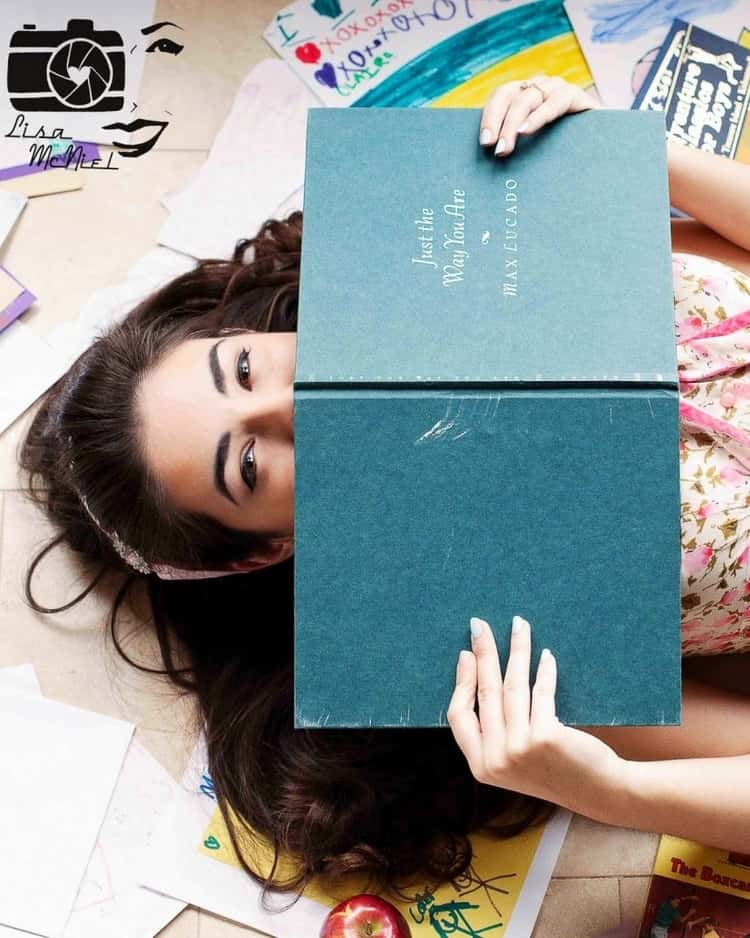 senior picture ideas for girls - upper-half body shot of girl lying down with open book partially covering her face from the nose downwards 