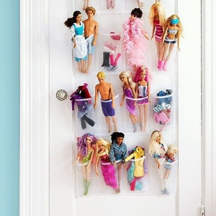organizing toys using a clear shoe organizer hanging on the back of a door with dolls and accessories