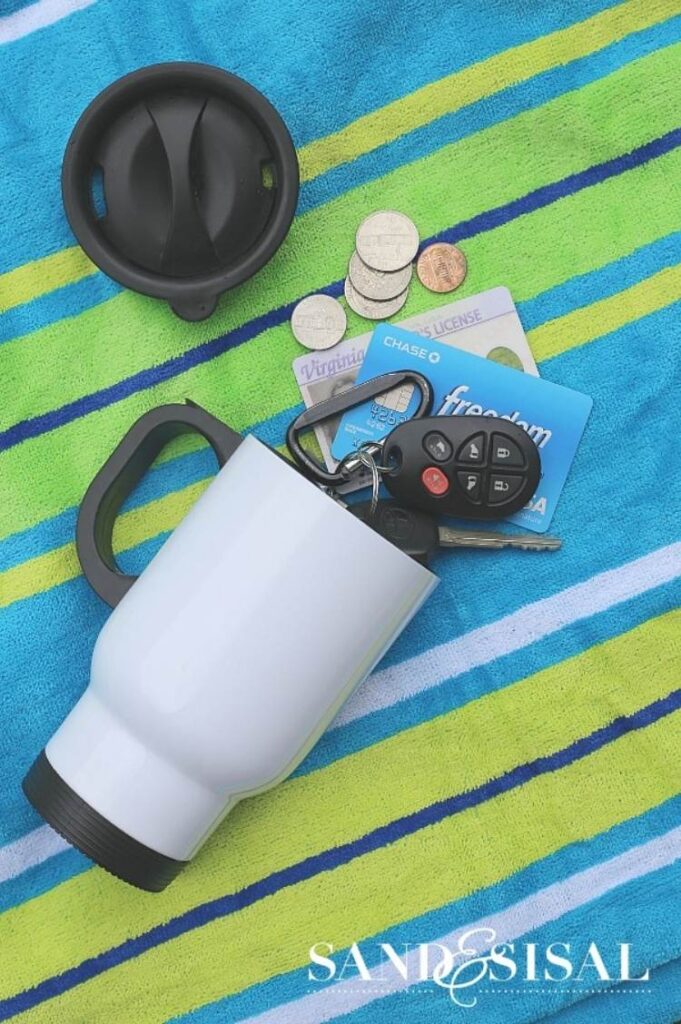 ids, keys, and cash hidden in a coffee cup at the beach