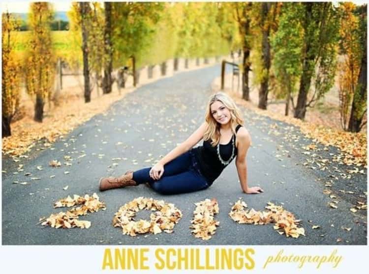 girl seated on road with fall leaves spelling the year 2014 in numbers 