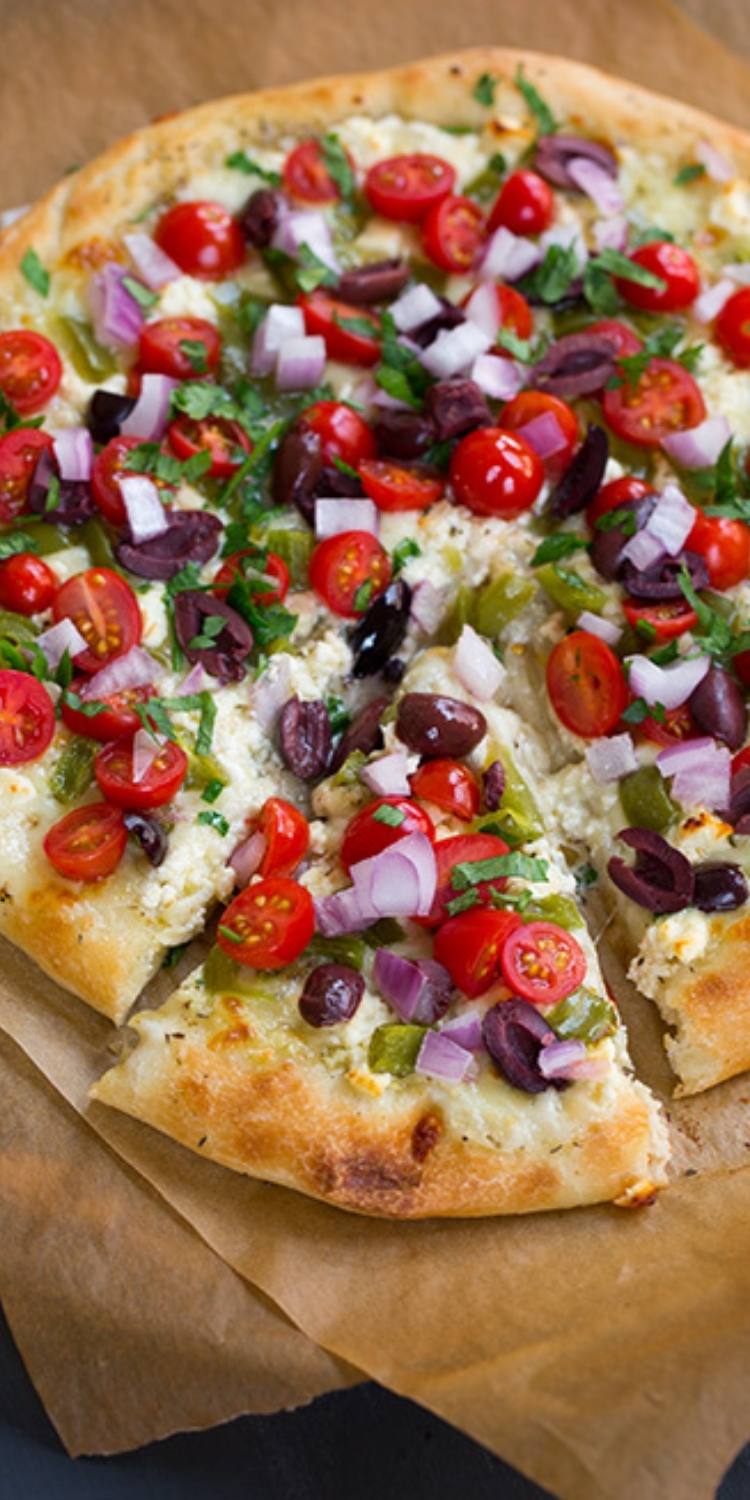 Greek salad pizza ideas. Tomatoes, onions, olives, and basil atop a flatbread pizza crust. 