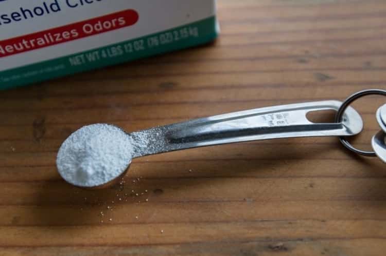 a measuring spoon containing a white powdery substance that's laid on wooden table 