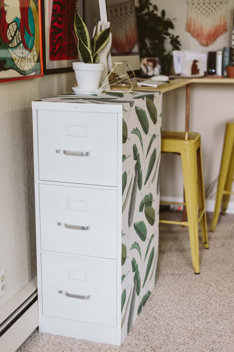 light blue modern file cabinet for home office who's visible side is decorated with large green leaf prints 